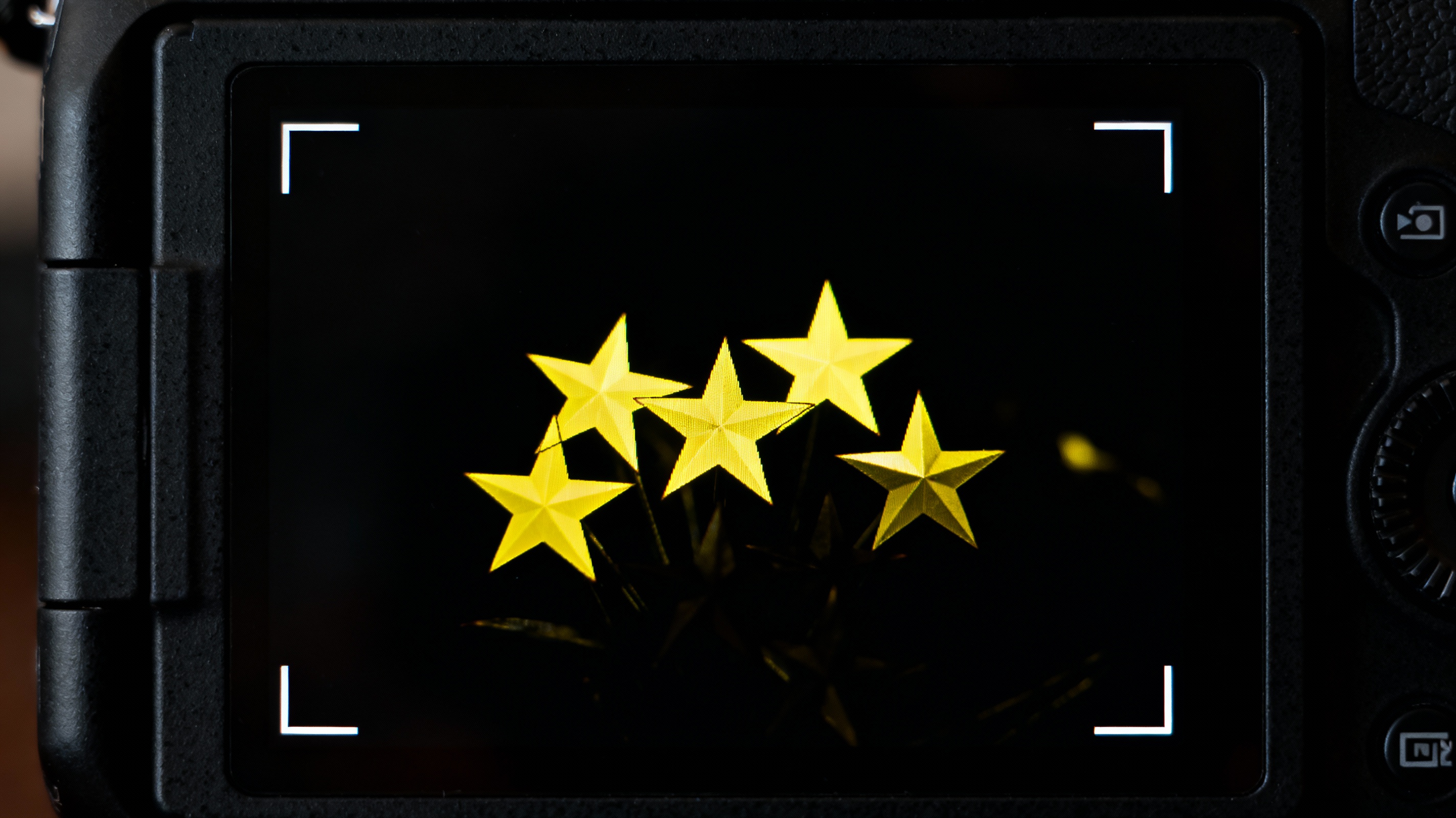 Close-up of a camera’s LCD screen showing a cluster of stars, with bright yellow focus peaking highlights outlining their sharp edges. The background is pitch black, emphasizing the stars’ crispness.